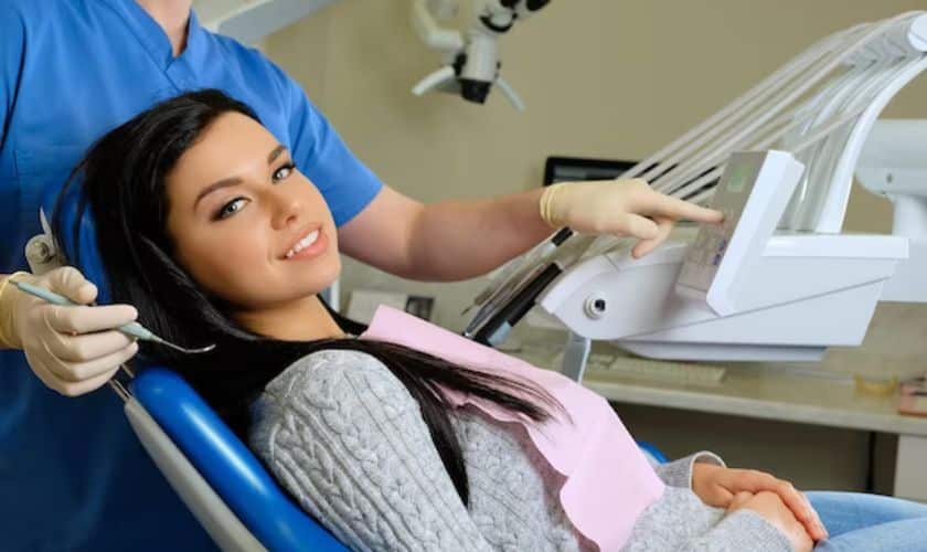 Female patient receiving dental examination in dentist's chair while dental professional works with instruments.