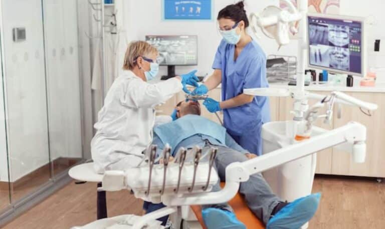 Pediatric dentist examining young child's teeth in modern dental office treatment room.