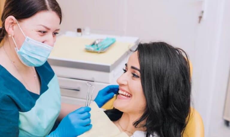 Dental hygienist in blue mask examining patient's teeth in professional office setting.
