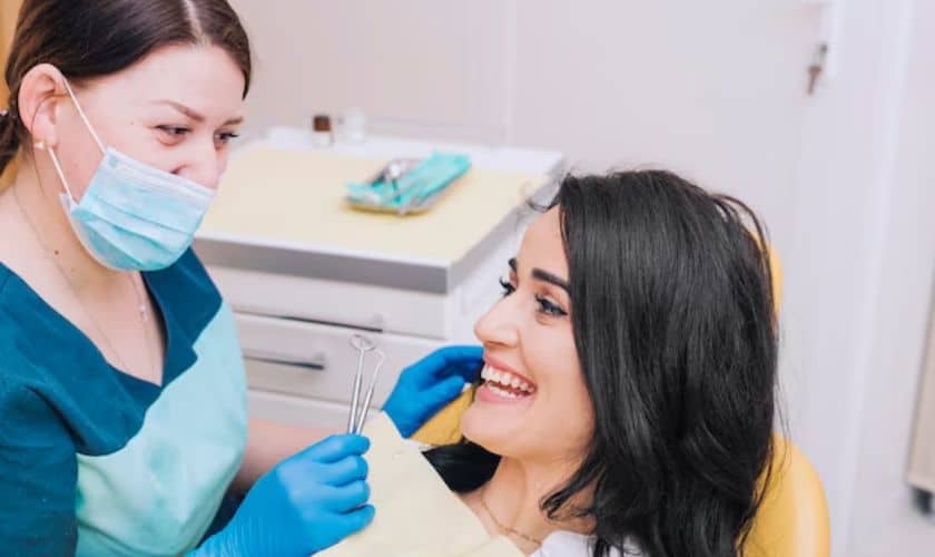 Dental hygienist in blue mask examining patient's teeth in professional office setting.