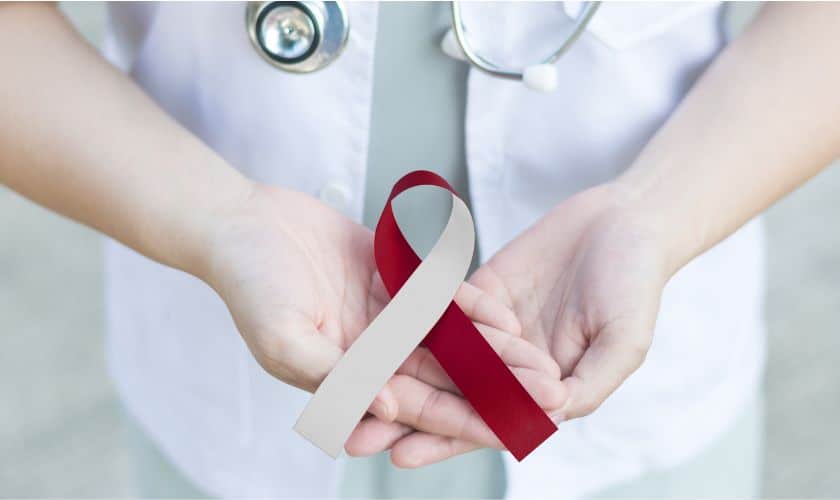 Healthcare professional holding red awareness ribbon symbolizing medical support and dental care advocacy.